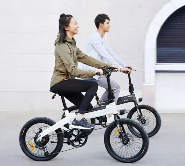 a man and woman riding the himo c20 electric bike